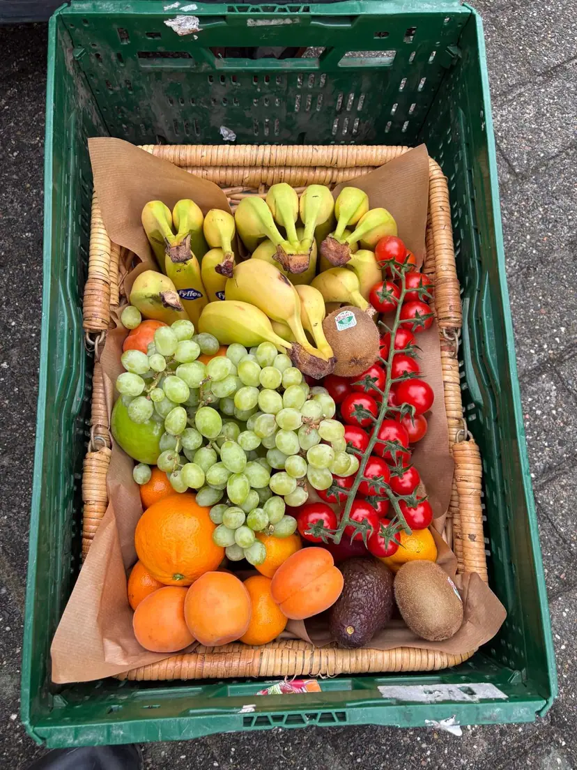Een mand met bananen, druiven, kiwi's en mandarijnen